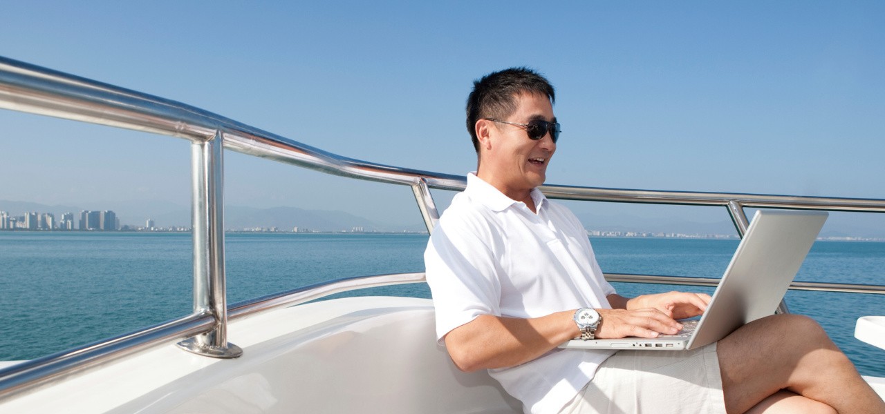 man on yacht using laptop